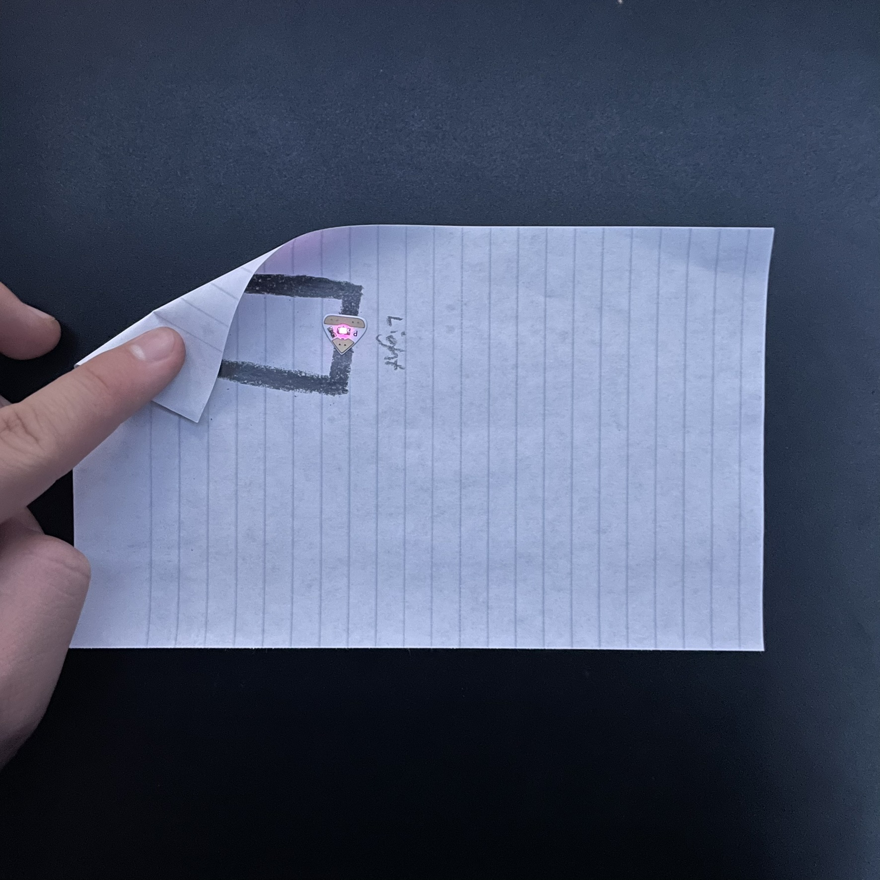 The circuit is being activated here and needs the paper to be folded to touch the top of the battery as the positive side